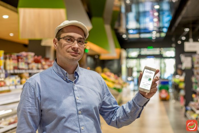 Ivo Dimitrov, holding CozZo app in a supermarket.